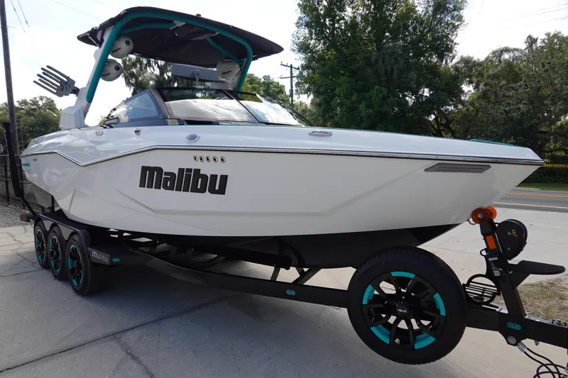 Slide: The Image of 2023 Malibu 25 LSV boat on trailer, white exterior, teal accents. - 4