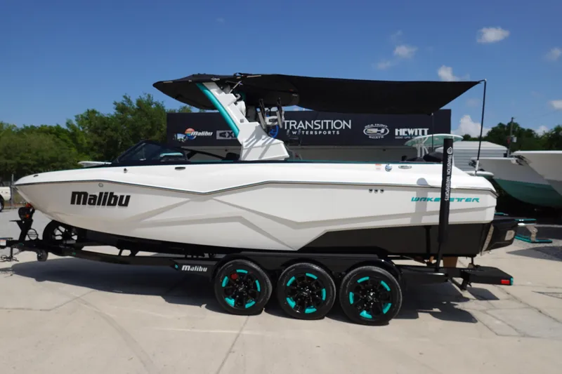 Slide: The Image of 2023 Malibu 25 LSV boat on a trailer with teal-accented wheels. - 40