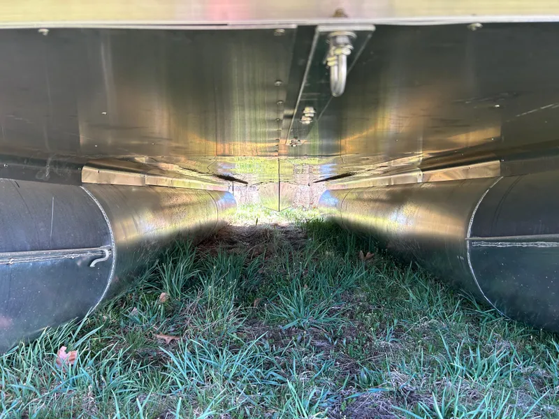 Slide: The Image of Underneath view of 2024 Bentley Pontoons Legacy Swingback 220, showing pontoons and grass. - 17