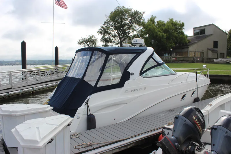 Slide: The Image of 2011 Rinker 310 Express Cruiser docked at a marina with a covered cockpit. - 13