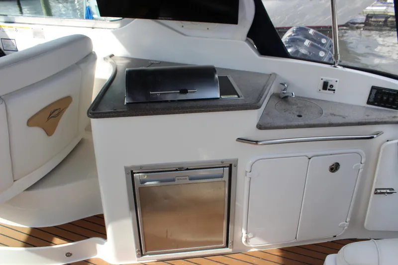 Slide: The Image of 2011 Rinker 310 Express Cruiser cockpit with mini kitchen and sink. - 18