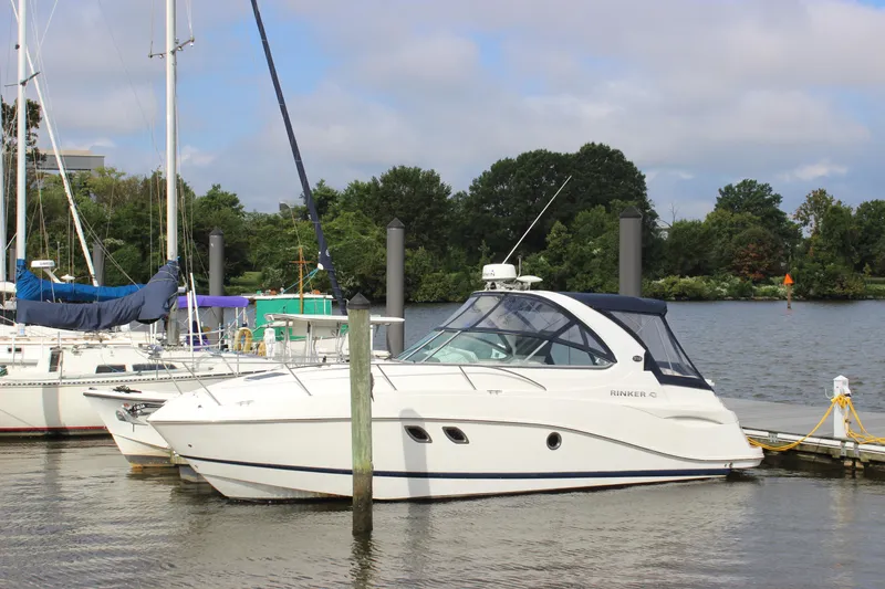 Slide: The Image of 2011 Rinker 310 Express Cruiser docked at a marina with sailboats in the background. - 2