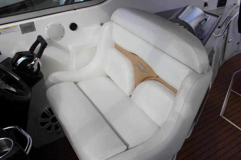 Slide: The Image of 2011 Rinker 310 Express Cruiser helm seat with white upholstery and wooden deck. - 27