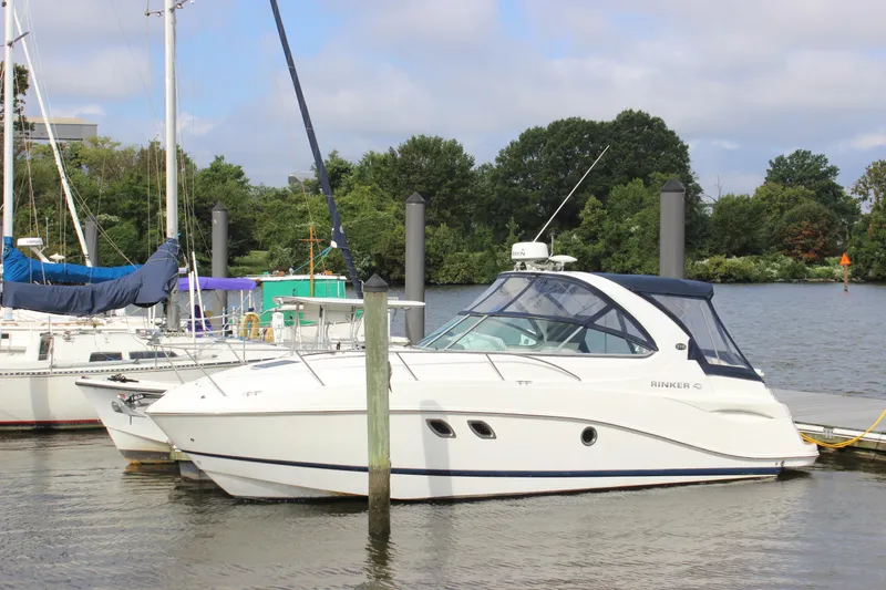 Slide: The Image of 2011 Rinker 310 Express Cruiser docked at a marina with sailboats in the background. - 4