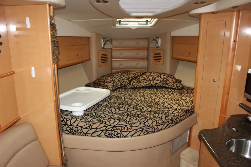 Slide: The Image of 2011 Rinker 310 Express Cruiser cabin with bed, kitchenette, and wood cabinetry. - 46