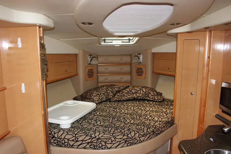 Slide: The Image of 2011 Rinker 310 Express Cruiser cabin with bed and storage cabinets. - 47