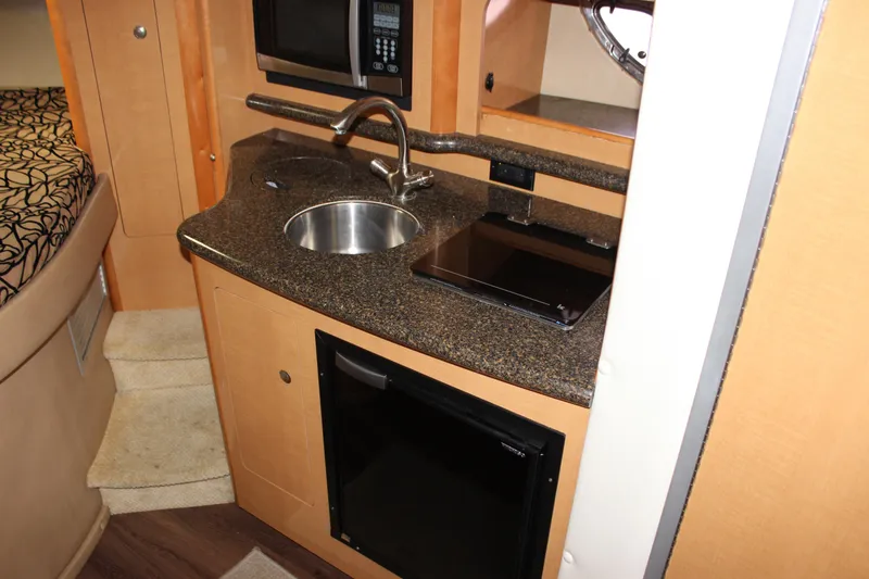 Slide: The Image of 2011 Rinker 310 Express Cruiser kitchenette with sink, microwave, and mini-fridge. - 48