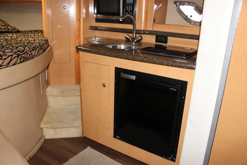 Slide: The Image of 2011 Rinker 310 Express Cruiser interior kitchen with sink, microwave, and refrigerator. - 49