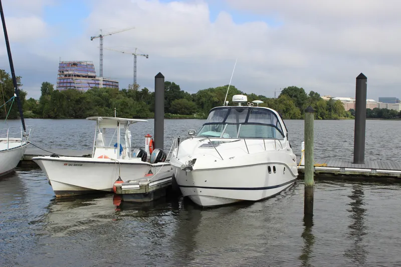 Slide: The Image of 2011 Rinker 310 Express Cruiser docked beside another boat on a calm river. - 8