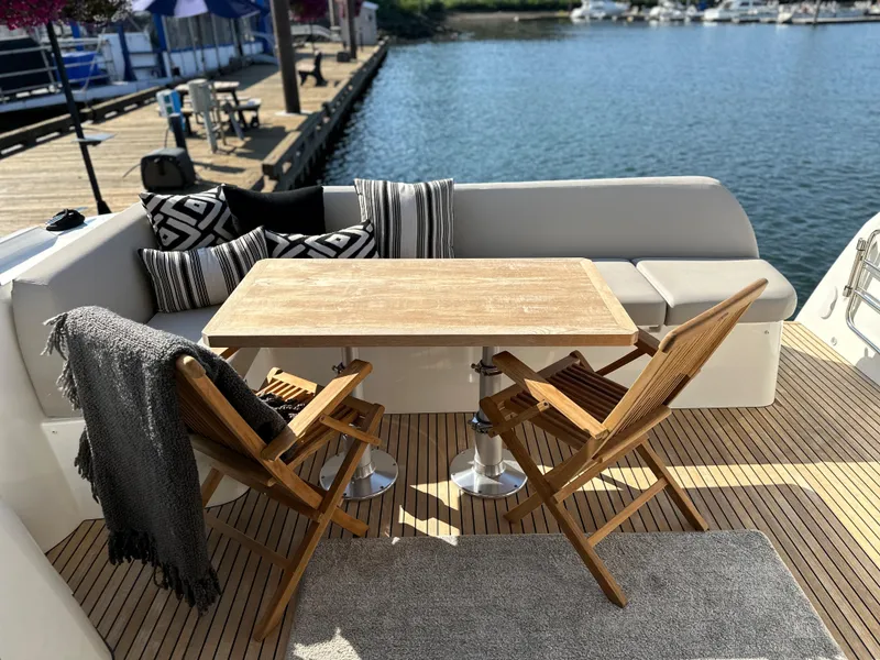 Slide: The Image of Prestige 420 S 2021 yacht deck with wooden table, chairs, and waterfront view. - 14