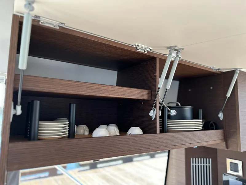 Slide: The Image of Open kitchen cabinet in a 2021 Prestige 420 S yacht with dishes and cookware. - 20
