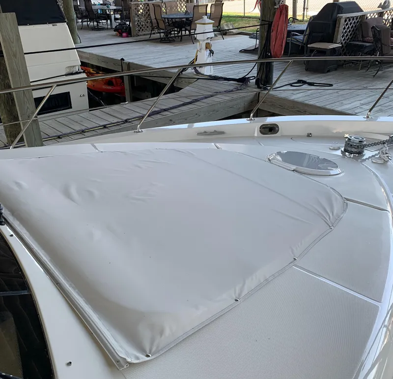 Slide: The Image of 2007 Carver 56 Voyager yacht deck with sunpad, docked near outdoor seating area. - 20