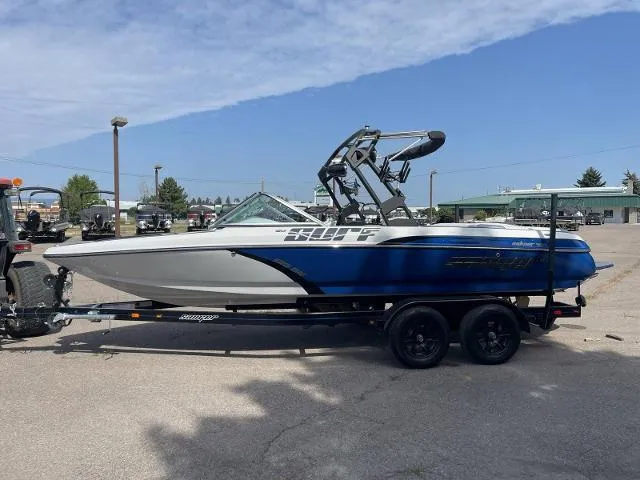 Slide: The Image of 2023 Sanger V215 SX boat on trailer, blue and white, parked outdoors. - 2