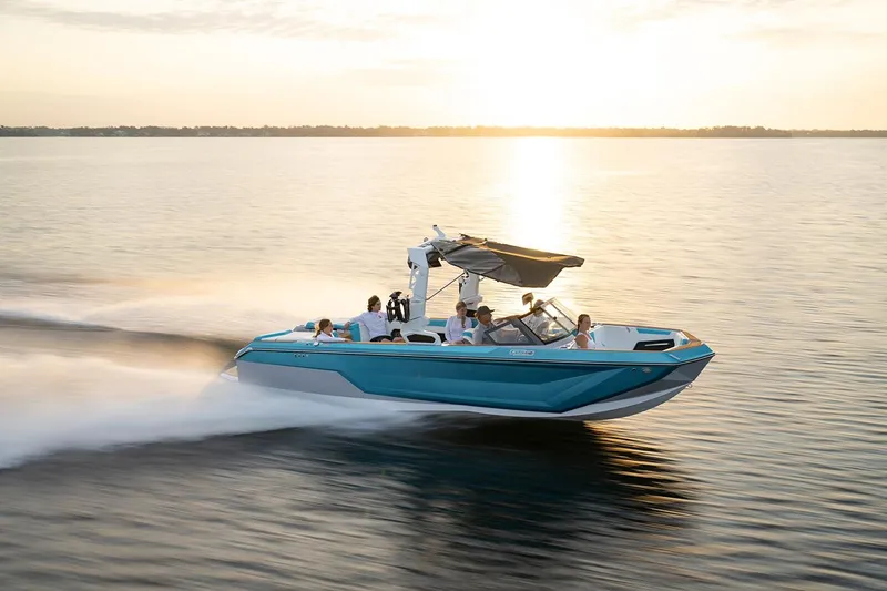 Slide: The Image of 2024 Nautique GS24 boat cruising on a lake at sunset. - 13