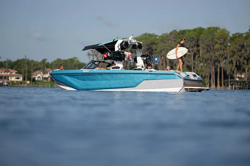 Slide: The Image of 2024 Nautique GS24 boat on a lake with people and a surfboard. - 14
