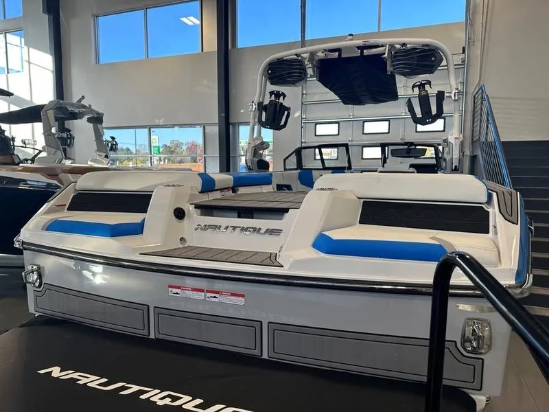 Slide: The Image of 2024 Nautique GS24 boat in showroom, rear view with blue and white seating. - 9