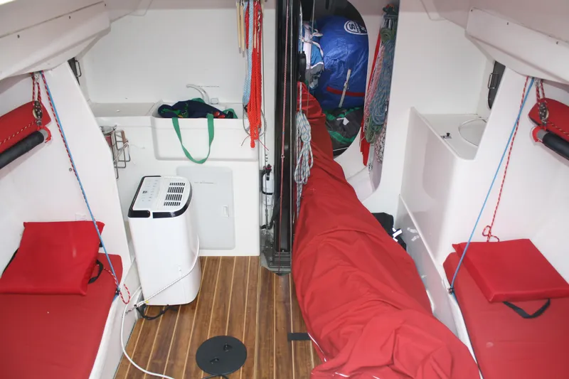 Slide: The Image of Interior of a 2004 Farr 40 sailboat with red cushions and wooden flooring. - 2