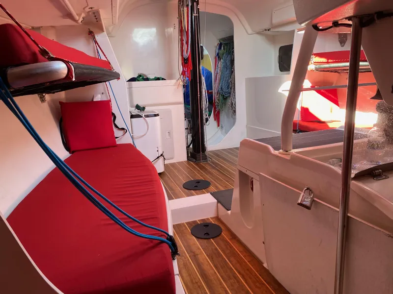 Slide: The Image of Interior of 2004 Farr 40 sailboat with red cushions and wooden flooring. - 29