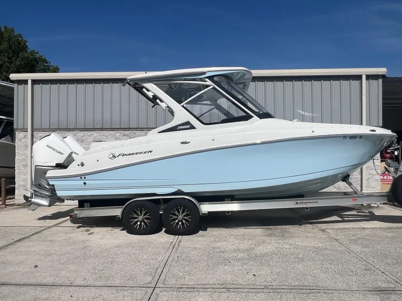 The Image of 2023 Finseeker 280 DC boat on trailer, light blue hull, parked outdoors. - 0