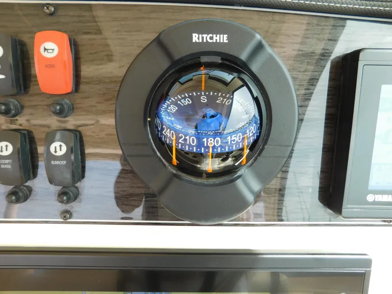 Slide: The Image of Ritchie compass on 2018 Grady-White Freedom 375 boat dashboard with control buttons. - 32