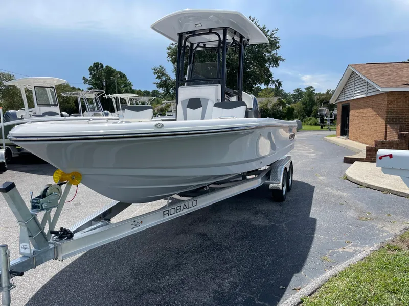 Slide: The Image of 2024 Robalo 226 Cayman boat on a trailer in a driveway. - 2