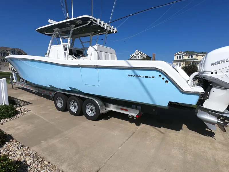 Slide: The Image of 2019 Invincible 39 CC boat on trailer, light blue hull, parked in residential area. - 2