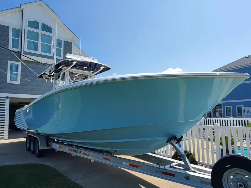 Slide: The Image of 2019 Invincible 39 CC boat on trailer, parked near coastal house. - 30