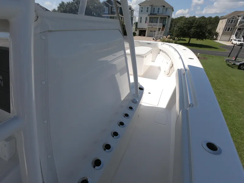 Slide: The Image of 2019 Invincible 39 CC boat deck with rod holders, residential backdrop. - 9