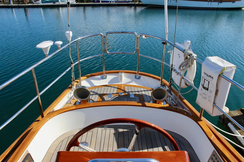 Slide: The Image of Cockpit view of 2018 Cape George 45 sailboat with wooden accents and marina backdrop. - 24