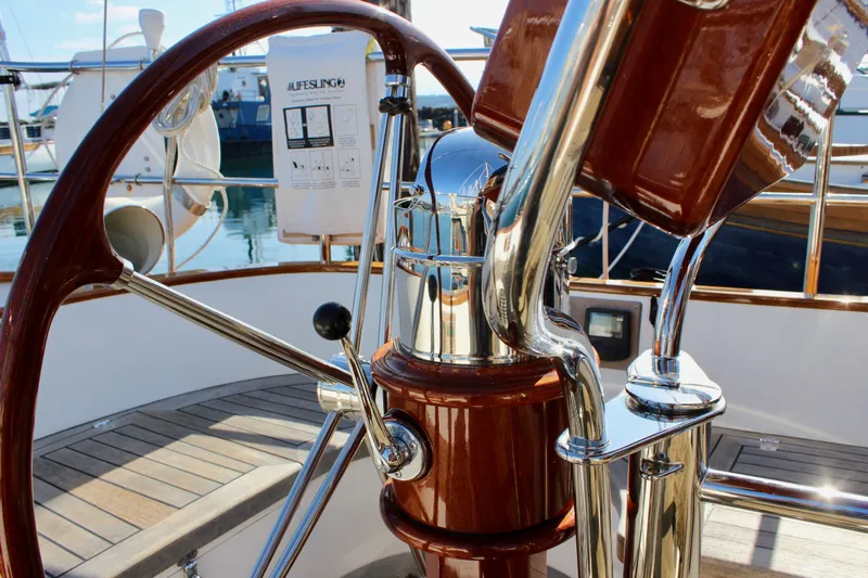 Slide: The Image of Steering wheel and controls of a 2018 Cape George 45 sailboat, featuring polished wood and metal. - 28