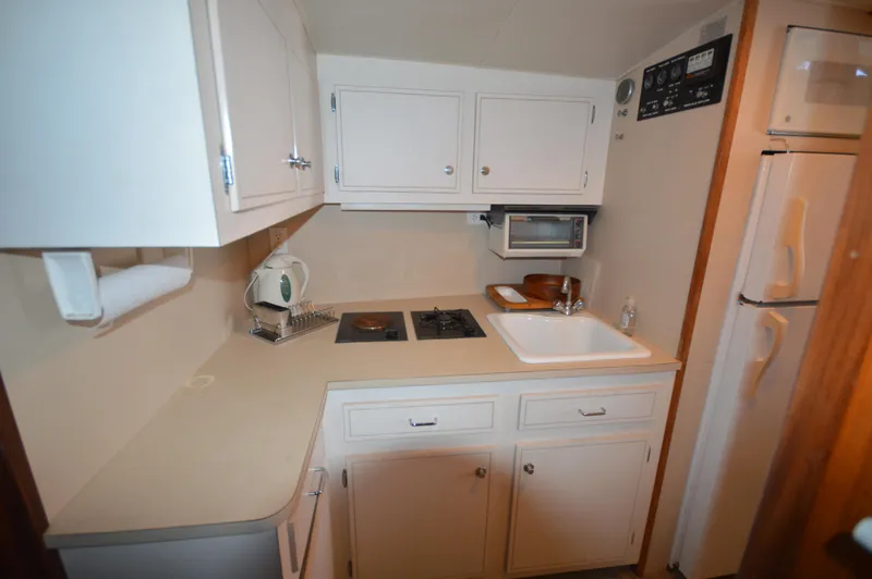 Slide: The Image of 1973 Hatteras 45 Convertible boat kitchen with white cabinets and appliances. - 24