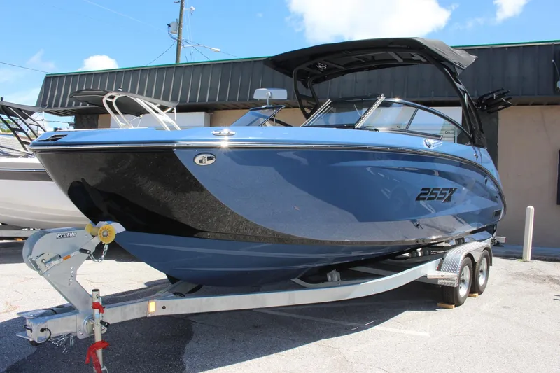 Slide: The Image of 2023 Yamaha Boats 255XD on trailer, blue and black, docked outdoors. - 0