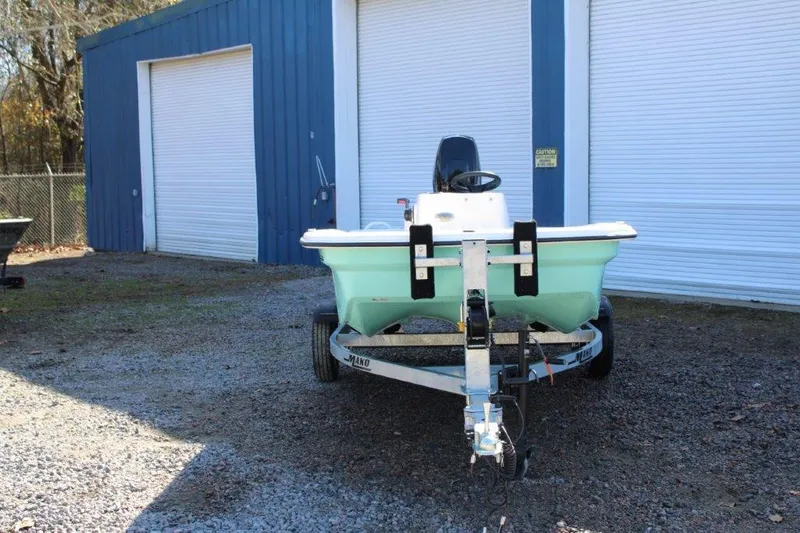 Slide: The Image of 2024 Mako Pro Skiff 13 CC boat on trailer in front of blue storage units. - 3
