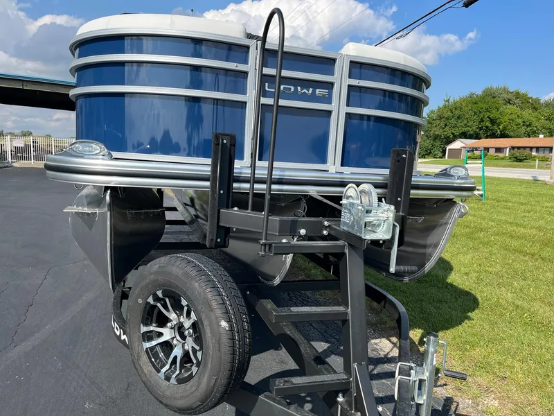 Slide: The Image of 2024 Lowe SS 210 WT pontoon boat on a trailer, blue exterior, sunny day. - 31