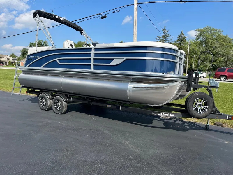 Slide: The Image of 2024 Lowe SS 210 WT pontoon boat on trailer, blue and silver, outdoor display. - 5