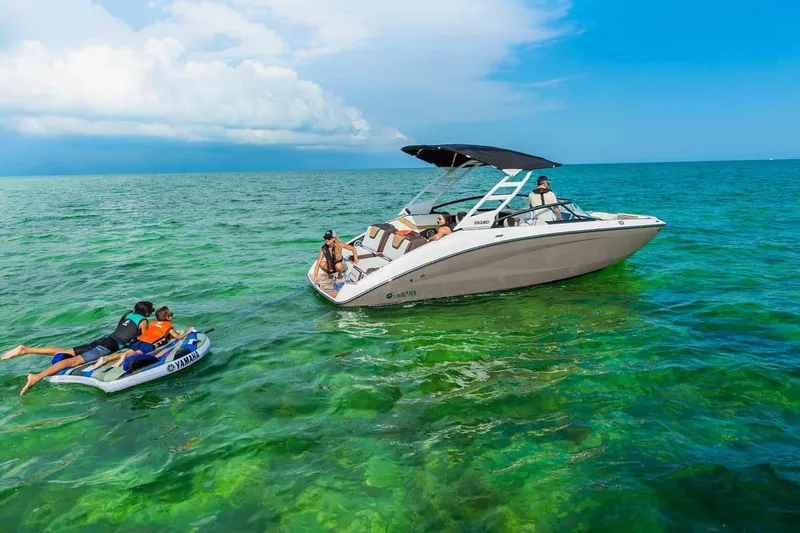 Slide: The Image of 2023 Yamaha Boats 252SD on clear water with people enjoying water activities. - 2