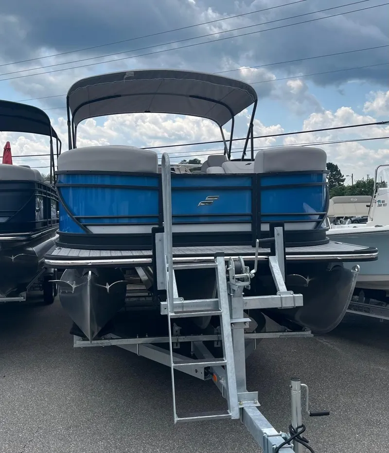 Slide: The Image of 2024 Starcraft SLS 3 pontoon boat on a trailer under a cloudy sky. - 2