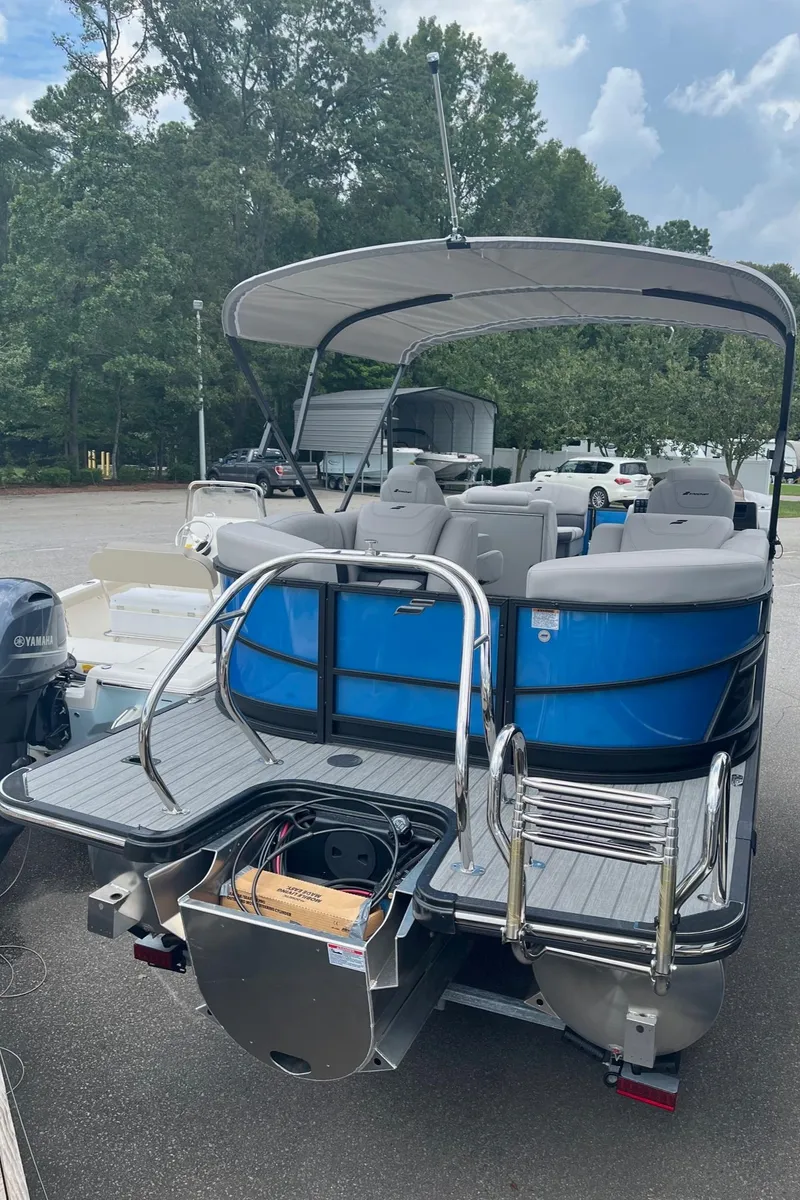 Slide: The Image of 2024 Starcraft SLS 3 pontoon boat with blue and gray seating, docked on a sunny day. - 4