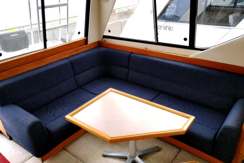Slide: The Image of Interior of 1995 Bayliner 3988 Motoryacht with blue L-shaped sofa and wooden table. - 17