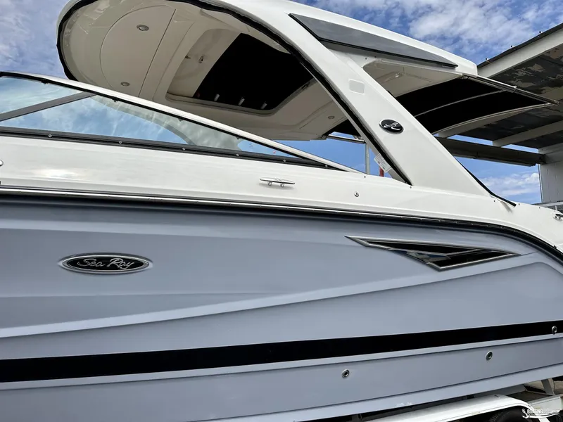 Slide: The Image of 2024 Sea Ray 310 SLX boat, sleek design, white exterior, under blue sky. - 2