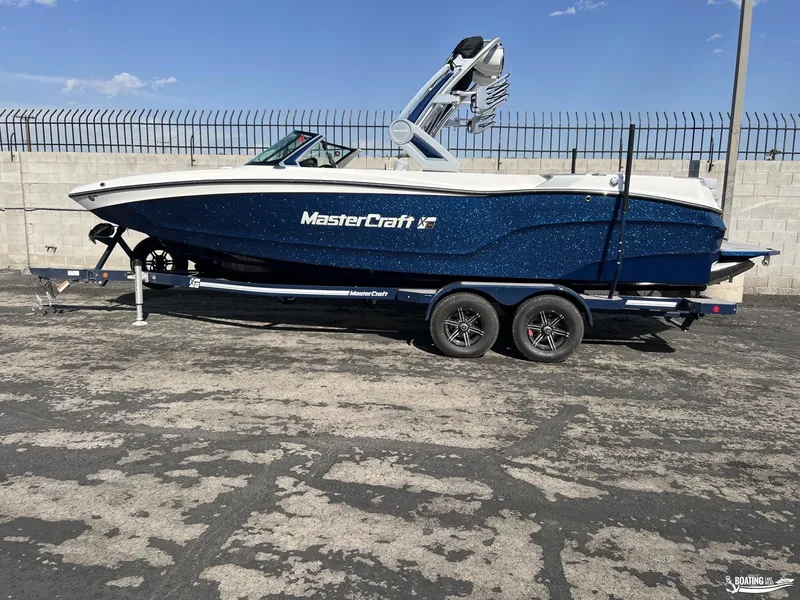 Slide: The Image of 2023 MasterCraft XT24 boat on trailer, parked outdoors. - 0