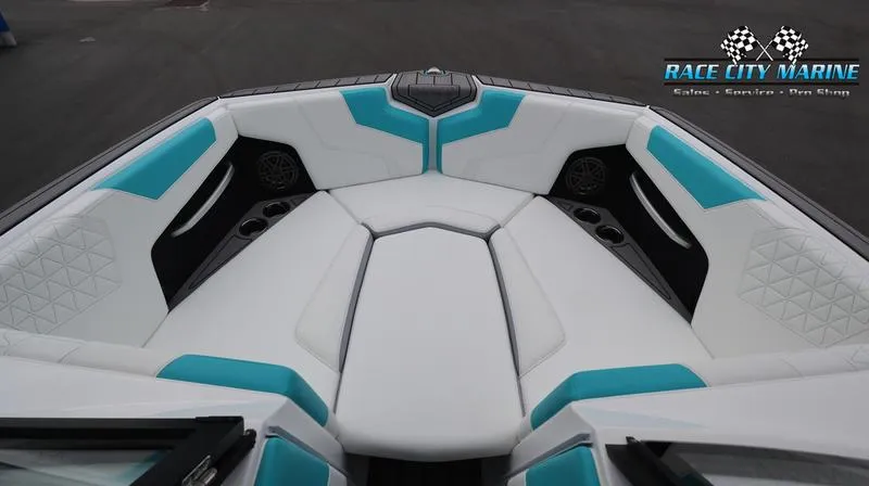 Slide: The Image of 2024 Nautique GS22 boat interior with white and teal seating, cup holders, and speakers. - 32