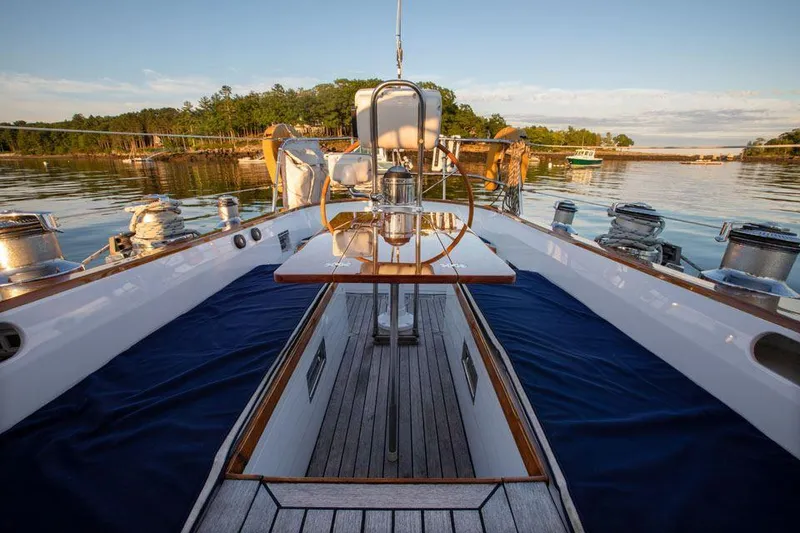 Slide: The Image of Hinckley OceanCruising 52 yacht deck, 1997 model, with wooden steering wheel and serene water backdrop. - 39