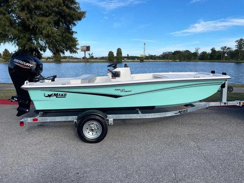 Slide: The Image of 2024 Mako Pro Skiff 13 CC boat on trailer by a lake. - 1