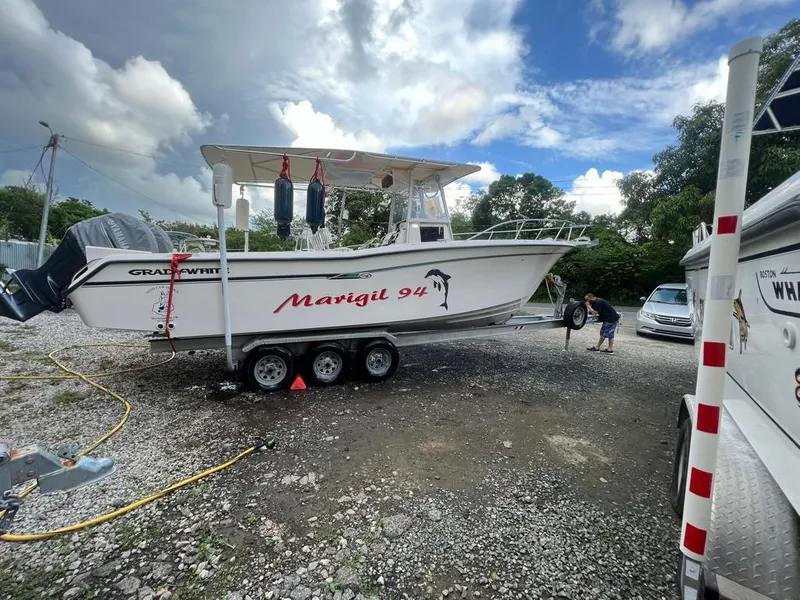 The Image of 1995 Grady-White Chase 263 boat on trailer, labeled "Marigit 94," under cloudy sky. - 0
