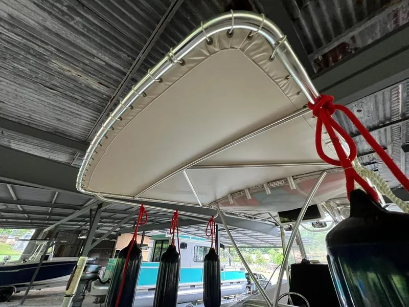 Slide: The Image of 1995 Grady-White Chase 263 boat under metal roof, featuring canopy and hanging fenders. - 13