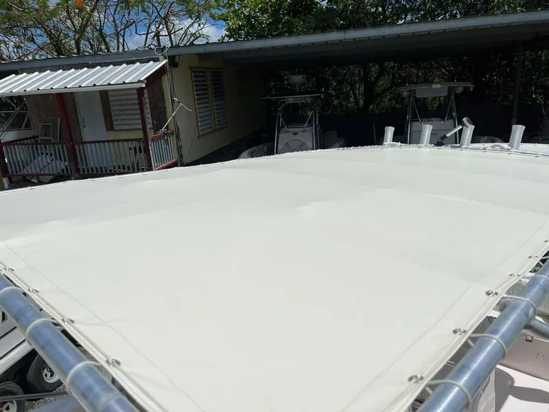 Slide: The Image of 1995 Grady-White Chase 263 boat with a white canopy, parked near a house. - 8