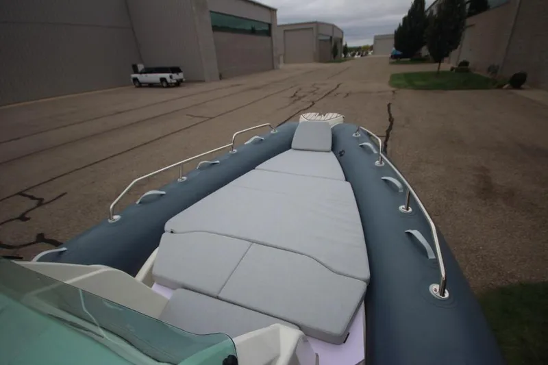Slide: The Image of 2024 Zodiac Medline 7.5 NEO boat with cushioned deck, parked near industrial buildings. - 25