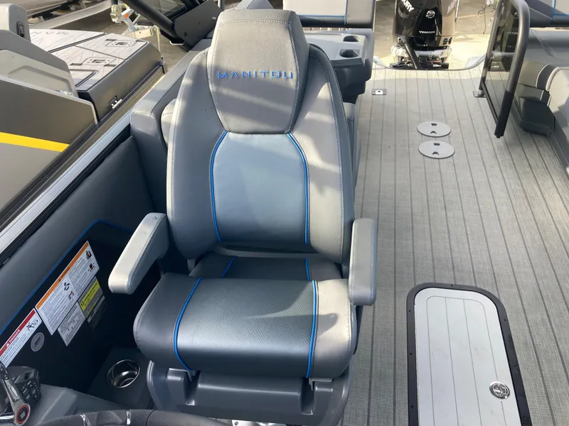 Slide: The Image of 2024 Manitou 24 EXPLORE SWITCHBACK boat seat with gray upholstery and blue accents. - 17