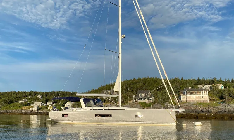 Slide: The Image of 2019 Beneteau 51.1 sailboat anchored near scenic shoreline under blue sky. - 1